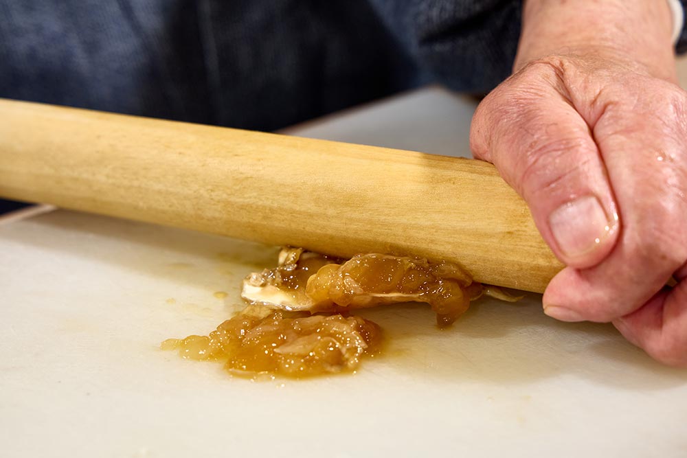 ワタリガニの醤油漬の身をすりこ木で押し出す